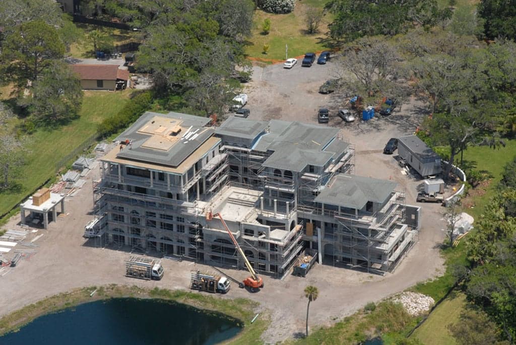 Aerial view of a multi-building property under construction beside a pond