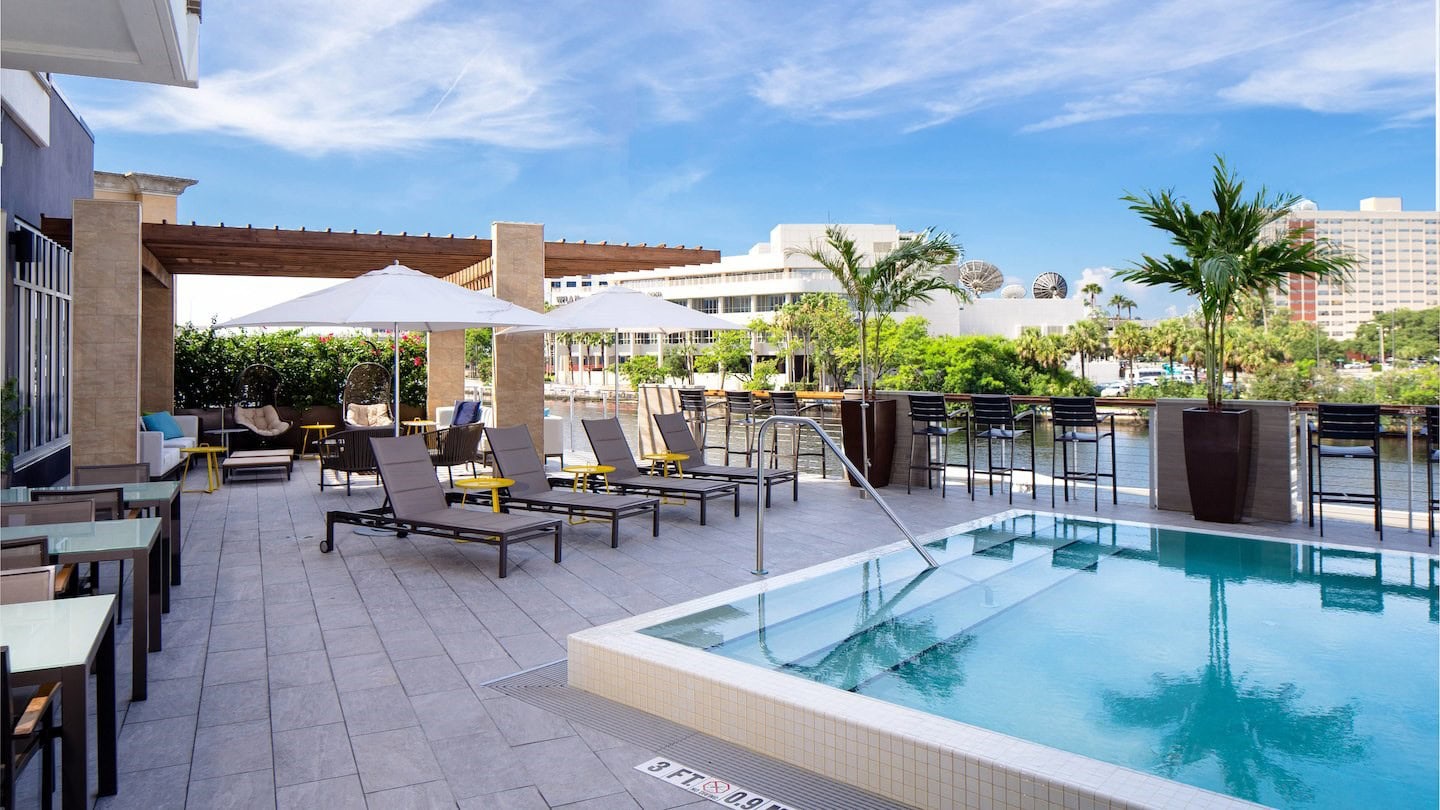 Hotel pool deck with loungers, umbrellas and a poolside bar