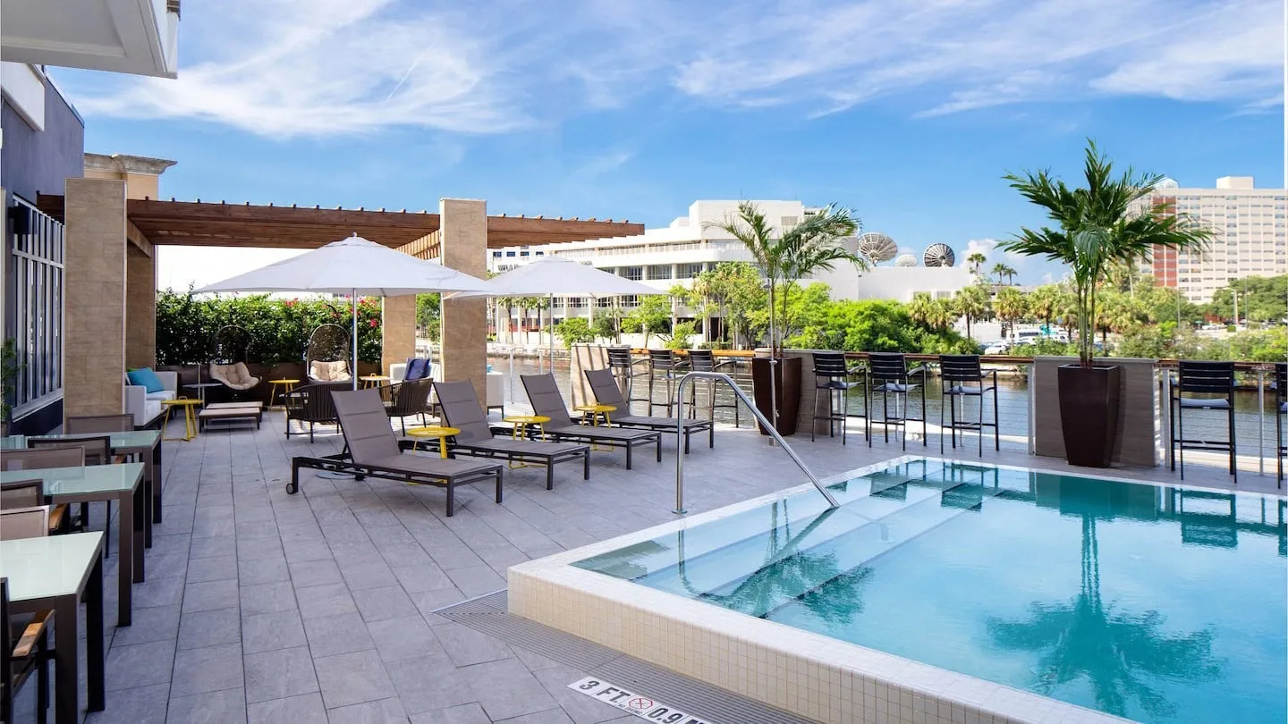 Hotel pool deck with loungers, umbrellas and a poolside bar