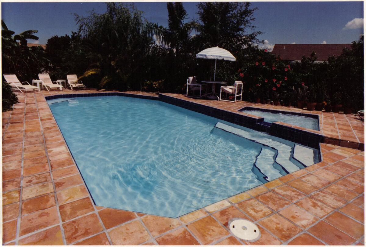 Rectangular pool and attached spa on a terracotta paver deck