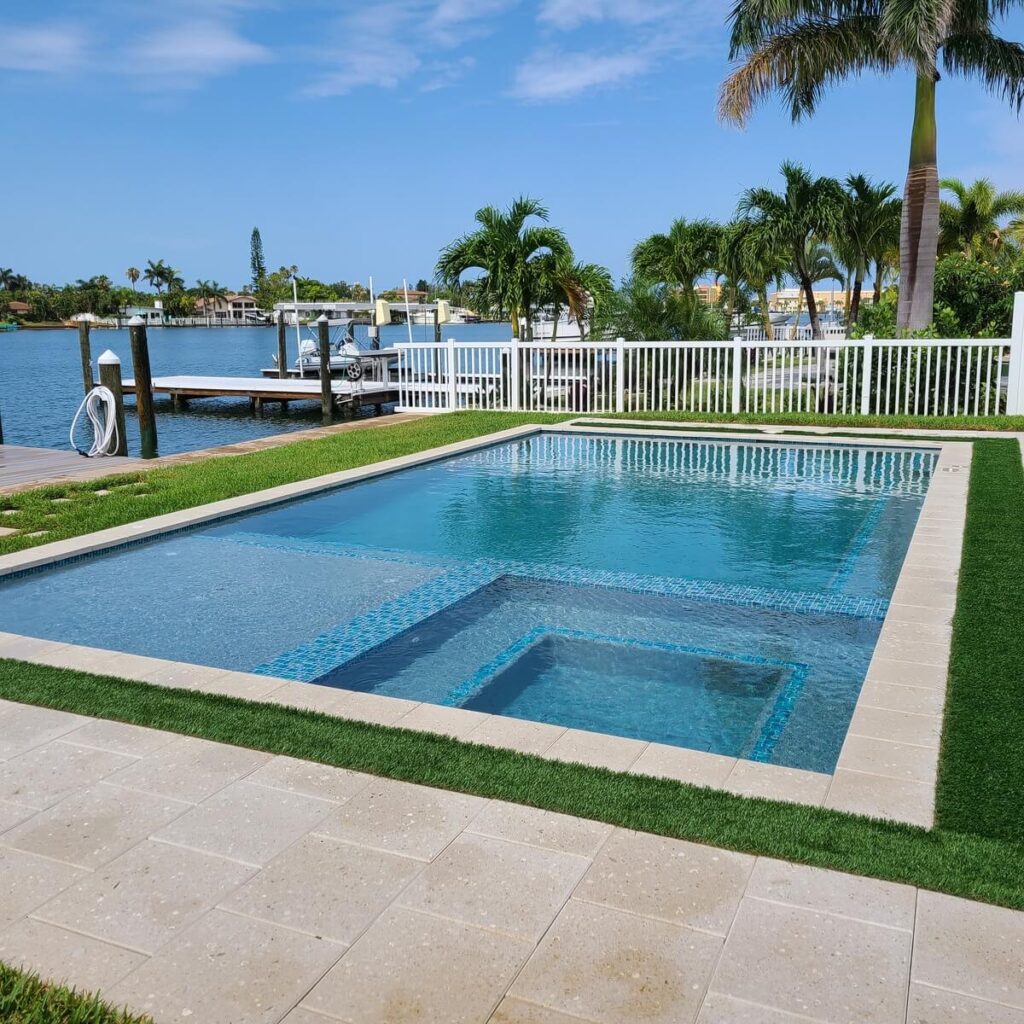 Rectangular pool with a raised spa beside a seawall and private dock