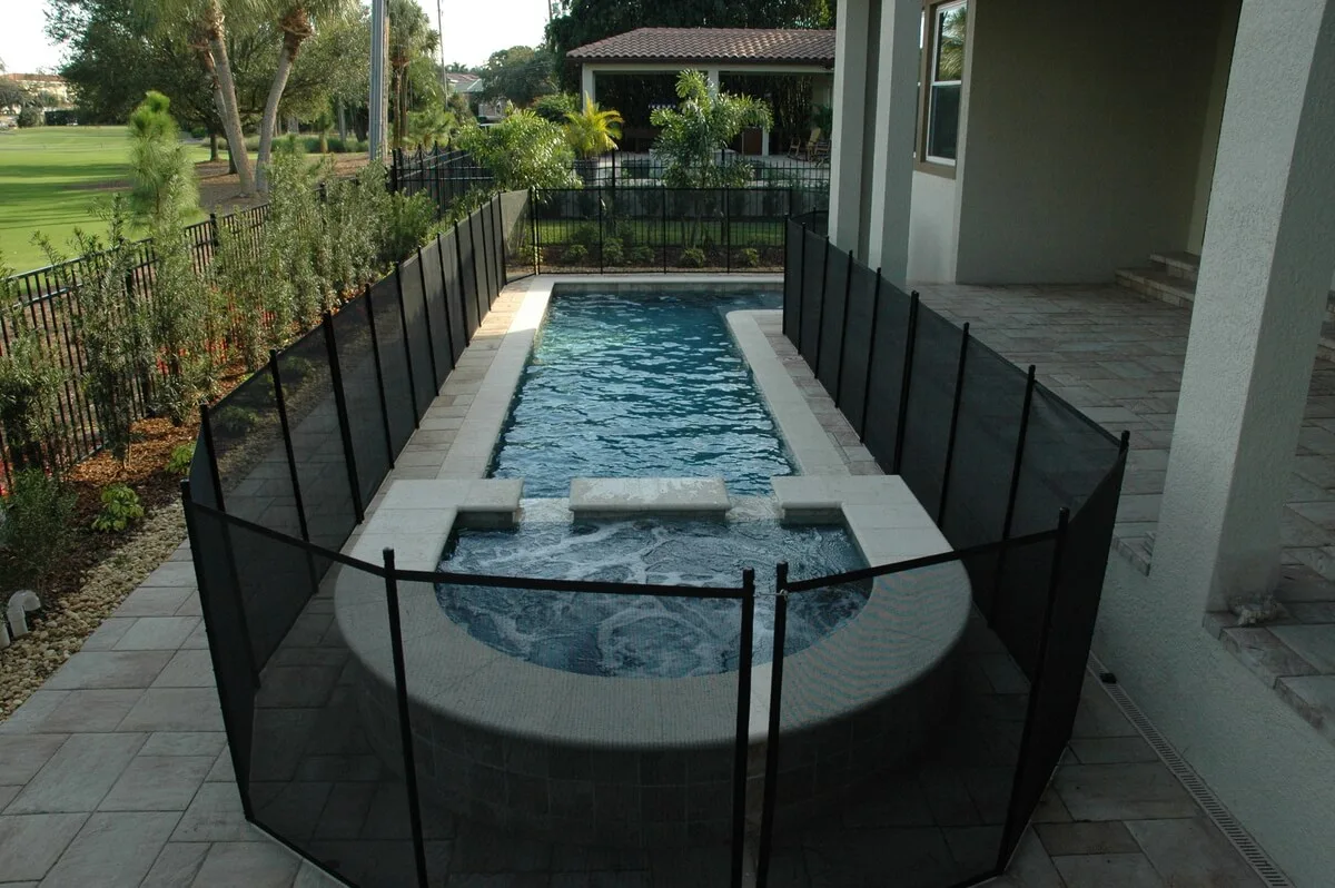 Pool and spa enclosed by a black removable safety fence